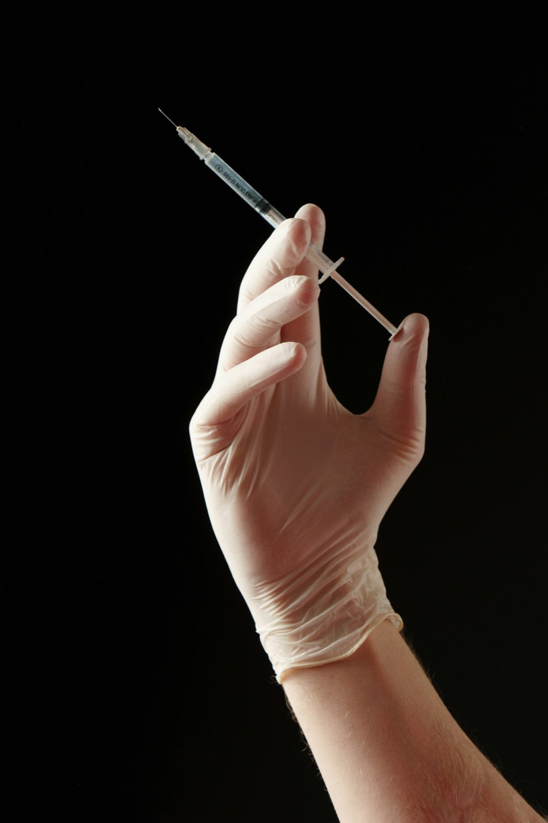 Gloved hand holding hypodermic needle for Cyro-Weld™ UV medical adhesive needle hub bonding and syringe assembly